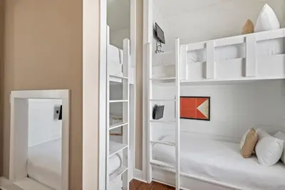 a bedroom with white bunk beds and a mirror at Waves in Santa Rosa Beach