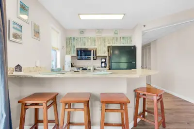a kitchen with wooden stools and a counter with a counter top at St Thomas Square Villa 1211C Beach Bumz in Panama City Beach