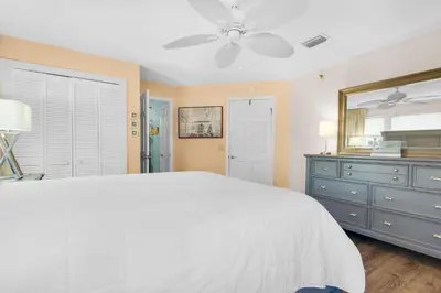 a bedroom with a white bed and a dresser and a mirror at St Thomas Square Villa 1211C Beach Bumz in Panama City Beach