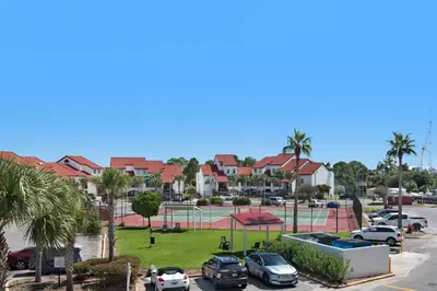 a parking lot with cars and a tennis court at St Thomas Square Villa 1211C Beach Bumz in Panama City Beach