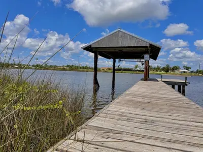 a wooden dock with a shelter on a body of water at Nautical Nirvana-Waterfront Joys from Sunrise Paddles to Hot Tub Sunsets in Panama City