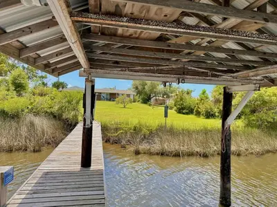 a wooden bridge over a river with a grass field at Nautical Nirvana-Waterfront Joys from Sunrise Paddles to Hot Tub Sunsets in Panama City