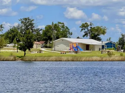 a house with a playground next to a lake at Nautical Nirvana-Waterfront Joys from Sunrise Paddles to Hot Tub Sunsets in Panama City