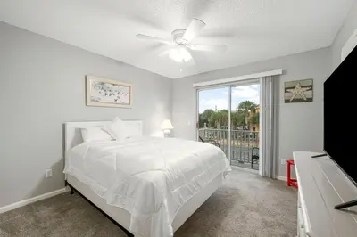 a white bedroom with a bed and a window at Barefoot Bungalow in Panama City Beach