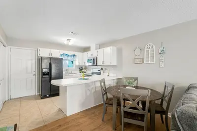 a kitchen and dining room with a table and a refrigerator at Barefoot Bungalow in Panama City Beach