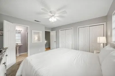 a bedroom with a white bed and a ceiling fan at Barefoot Bungalow in Panama City Beach