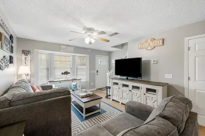 a living room with two couches and a flat screen tv at Barefoot Bungalow in Panama City Beach
