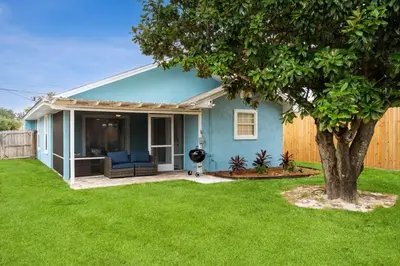 a blue house with a tree in a yard at March Sale! Walk to Beach - Large Private Yard - Fire Pit - Dog Friendly in Panama City Beach