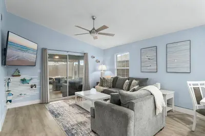 a living room with a couch and a ceiling fan at March Sale! Walk to Beach - Large Private Yard - Fire Pit - Dog Friendly in Panama City Beach