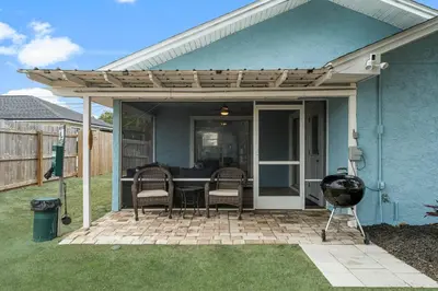 a patio with a table and chairs under a pergola at March Sale! Walk to Beach - Large Private Yard - Fire Pit - Dog Friendly in Panama City Beach