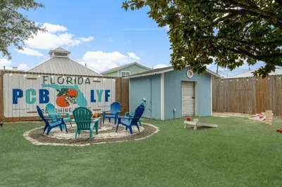 a patio with chairs and a table in a yard at March Sale! Walk to Beach - Large Private Yard - Fire Pit - Dog Friendly in Panama City Beach