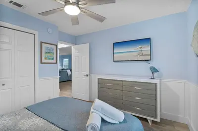 a bedroom with blue walls and a bed with a dresser at March Sale! Walk to Beach - Large Private Yard - Fire Pit - Dog Friendly in Panama City Beach