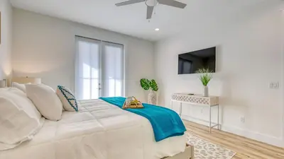 a white bedroom with a large bed and a tv at Joyful Sound by AvantStay Walk to the Beach in Panama City Beach