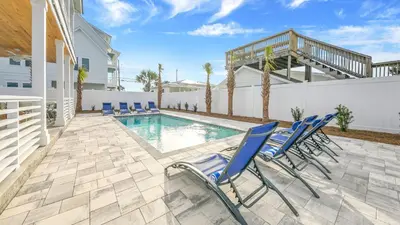 a patio with chairs and a swimming pool at Joyful Sound by AvantStay Walk to the Beach in Panama City Beach