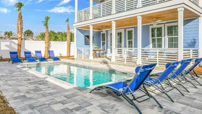 a group of blue chairs sitting around a swimming pool at Joyful Sound by AvantStay Walk to the Beach in Panama City Beach