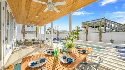 a patio with a wooden table and chairs on a deck at Joyful Sound by AvantStay Walk to the Beach in Panama City Beach