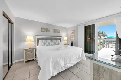 a bedroom with a white bed and a balcony at BeachCrest 101 - Directly on the beach in the heart of Seagrove Beach along 30A in Santa Rosa Beach
