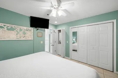 a bedroom with a white bed and a ceiling fan at Merrimac Resort #12 in Panama City Beach
