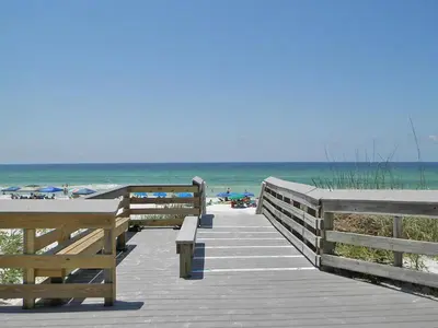 a wooden boardwalk leading to the beach with benches at Cassine Station 305 - Sea Ya in Santa Rosa Beach
