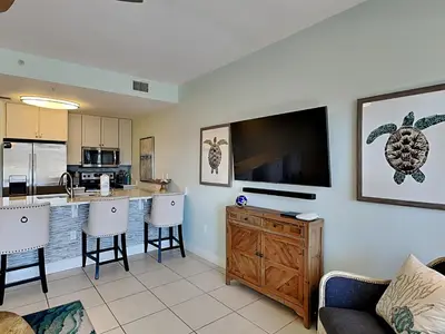 a living room with a kitchen with a large flat screen tv at Cassine Station 305 - Sea Ya in Santa Rosa Beach