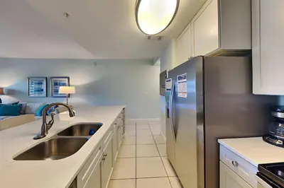 a kitchen with a sink and a stainless steel refrigerator at Cassine Station 305 - Sea Ya in Santa Rosa Beach