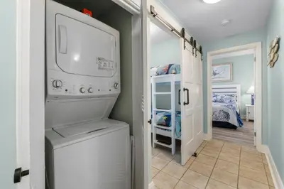 a laundry room with a washer and dryer and a bedroom at Coast is Clear at Laketown Wharf #1225 by Nautical Properties in Panama City Beach
