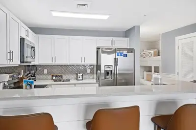 a kitchen with white cabinets and a stainless steel refrigerator at Calypso 3-2210 - Love Nest in Panama City Beach