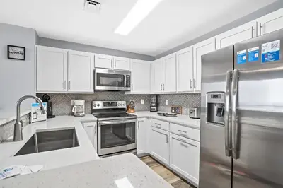a kitchen with white cabinets and a stainless steel refrigerator at Calypso 3-2210 - Love Nest in Panama City Beach