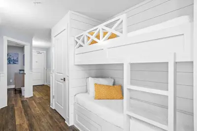 a white bedroom with a bunk bed with an orange pillow at Calypso 3-2210 - Love Nest in Panama City Beach