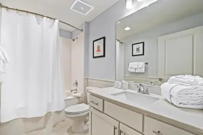 a white bathroom with a toilet and a sink at Calypso 3-2210 - Love Nest in Panama City Beach