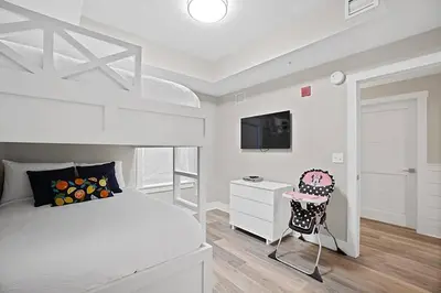 a white bedroom with a bed and a chair at Calypso 3-1601 - Corine's Corner in Panama City Beach