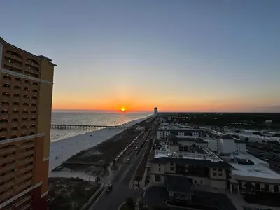 a sunset over the ocean and a beach with a city at Calypso 3-1601 - Corine's Corner in Panama City Beach