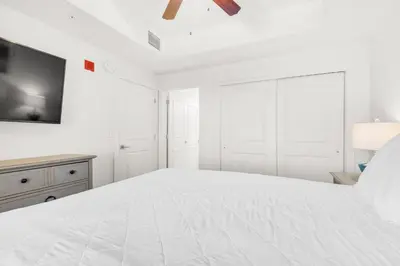 a white bedroom with a large bed and a tv at Calypso 3-1511 in Panama City Beach