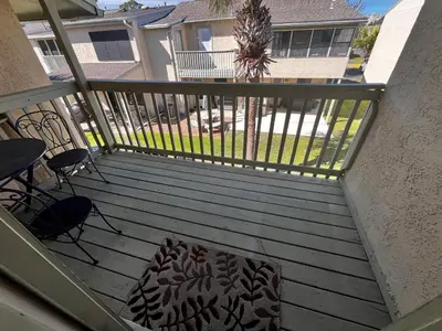 a balcony with a table and chairs and a palm tree at Sea & sand in Panama City Beach