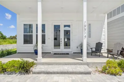 a white house with a porch and a chair at Laguna Beach Pearl by InJoy Vacations in Panama City Beach
