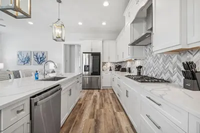 a white kitchen with white cabinets and wooden floors at Laguna Beach Pearl by InJoy Vacations in Panama City Beach