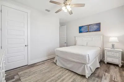 a white bedroom with a bed and a ceiling fan at Laguna Beach Pearl by InJoy Vacations in Panama City Beach