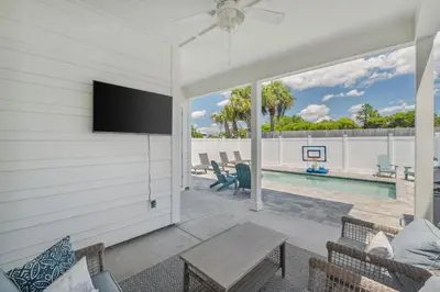 a living room with a tv and a pool at Laguna Beach Pearl by InJoy Vacations in Panama City Beach