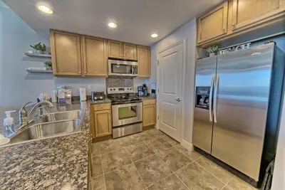 a kitchen with wooden cabinets and a stainless steel refrigerator at OCEAN FRONT CONDO w INCREDIBLE VIEWS in Panama City Beach