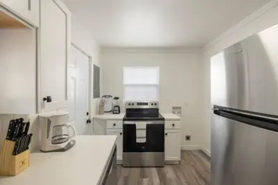a white kitchen with a stove and a refrigerator at The Coastal Cabana in Panama City Beach