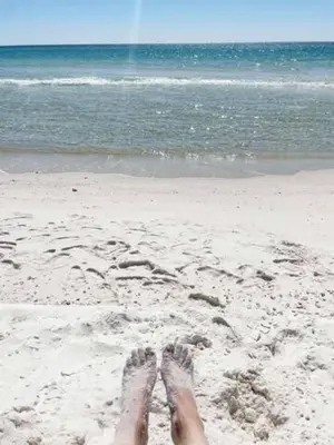 a persons feet in the sand on the beach at The Coastal Cabana in Panama City Beach