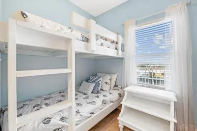 a bedroom with white bunk beds and a window at The Beach Scene at Laketown Wharf #524 by Nautical Properties in Panama City Beach