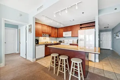 an open kitchen with wooden cabinets and bar stools at The Beach Scene at Laketown Wharf #524 by Nautical Properties in Panama City Beach
