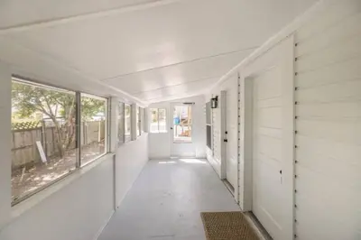 a hallway of a house with white walls and windows at The Coastal Shanty, yards from the beach in Panama City Beach