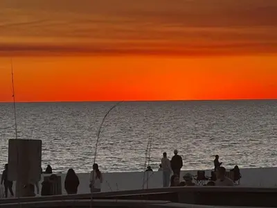a group of people standing on the beach at sunset at The Coastal Shanty, yards from the beach in Panama City Beach