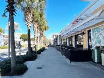 a sidewalk in front of a building with palm trees at The Coastal Shanty, yards from the beach in Panama City Beach