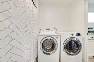 a white laundry room with a washer and dryer at The Coastal Shanty, yards from the beach in Panama City Beach