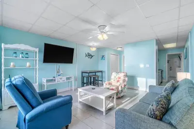 a living room with two blue chairs and a tv at Slice o’ Paradise - Gulf Front! Walk to Pier Park in Panama City Beach