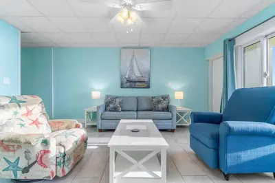 a living room with blue walls and a couch and a table at Slice o’ Paradise - Gulf Front! Walk to Pier Park in Panama City Beach