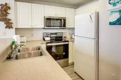 a kitchen with a white refrigerator and a sink at Balcony and Beach Access Oceanfront PCB Condo in Panama City Beach